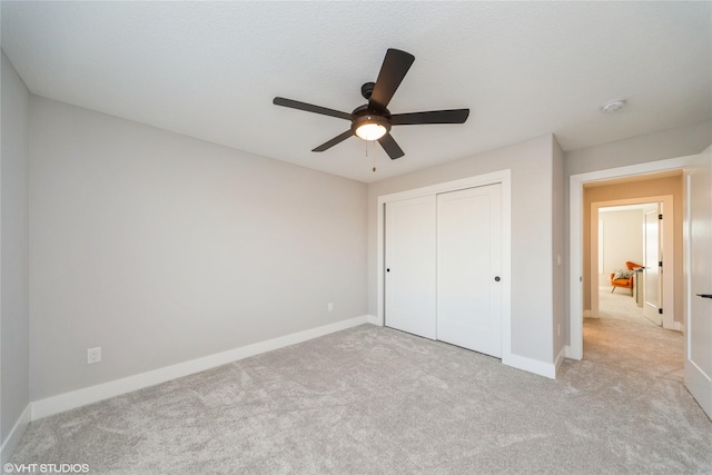 unfurnished bedroom with ceiling fan, baseboards, a closet, and light carpet