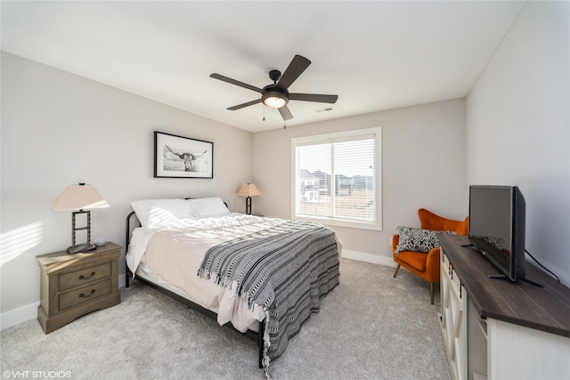 bedroom featuring light colored carpet, a ceiling fan, and baseboards