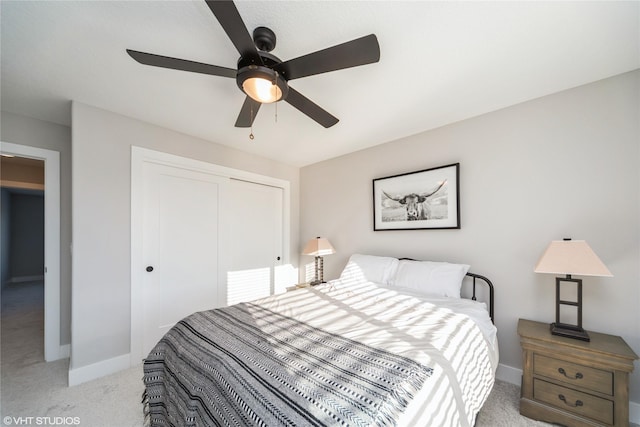 bedroom with a closet, ceiling fan, light carpet, and baseboards