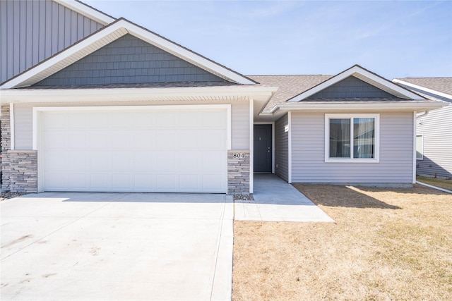 view of front of house featuring an attached garage, stone siding, and driveway