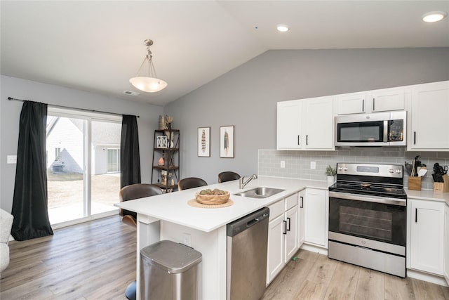 kitchen featuring a sink, appliances with stainless steel finishes, a peninsula, white cabinets, and light countertops