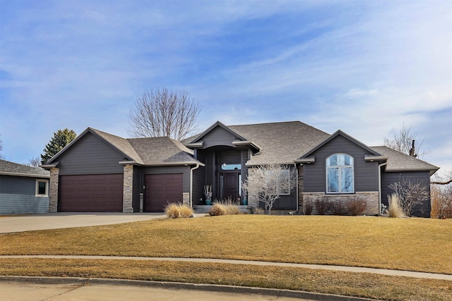 view of front of home with a shingled roof, a front lawn, concrete driveway, stone siding, and an attached garage