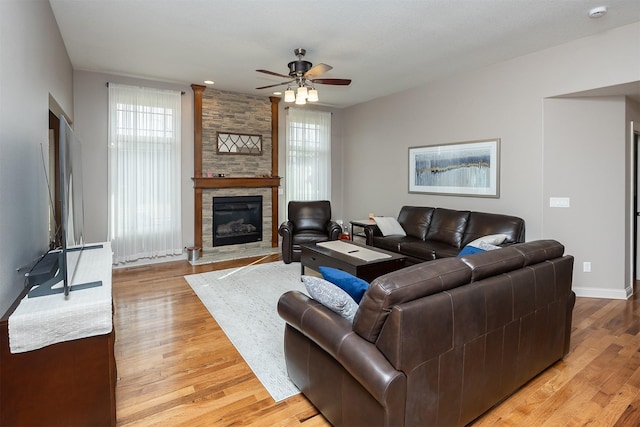 living room featuring a fireplace, baseboards, light wood-style floors, and ceiling fan