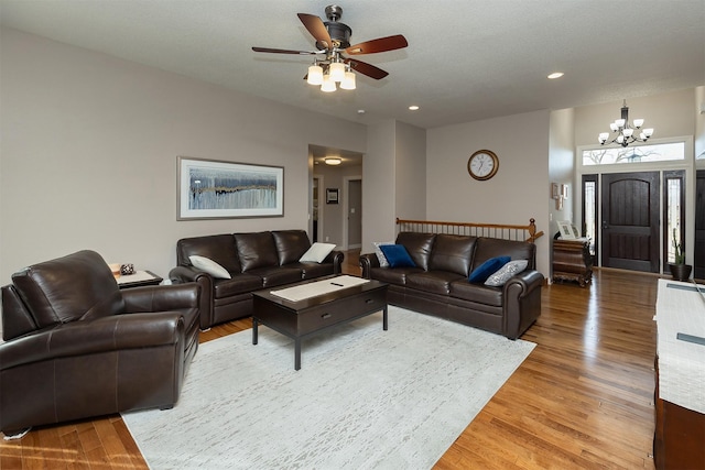 living room with recessed lighting, ceiling fan with notable chandelier, and light wood finished floors