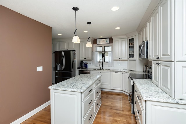 kitchen featuring a sink, white cabinets, appliances with stainless steel finishes, light wood-type flooring, and a center island