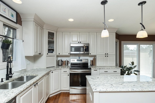 kitchen featuring dark wood finished floors, hanging light fixtures, appliances with stainless steel finishes, and a sink