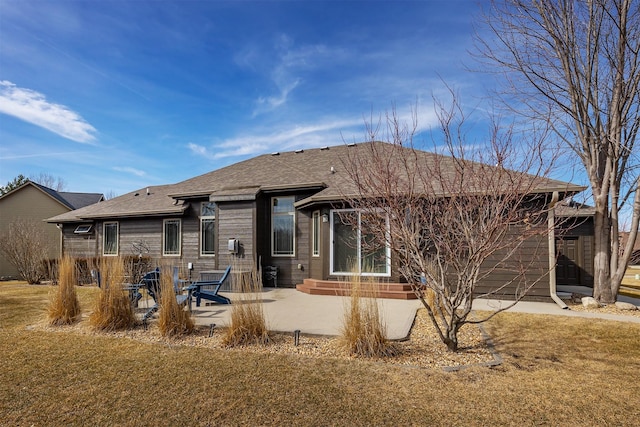 back of property featuring a patio area, a shingled roof, and a yard