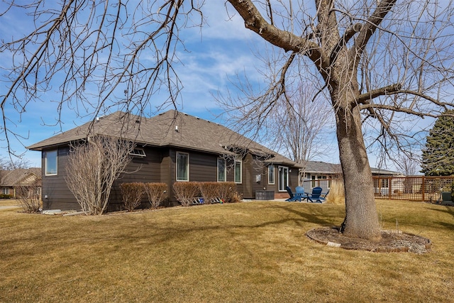 rear view of house featuring a patio area, a lawn, and a shingled roof