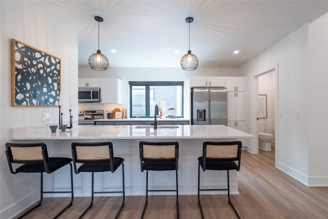 1201 Center St Unit F103, Des Moines, IA 50309 - kitchen featuring appliances with stainless steel finishes, a sink, a kitchen breakfast bar, light countertops, and white cabinets