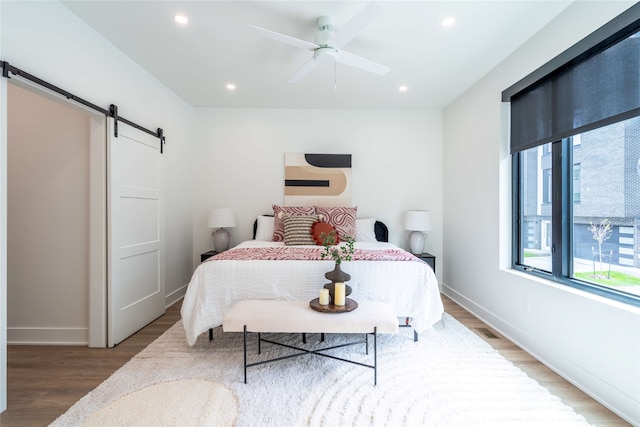 1201 Center St Unit F103, Des Moines, IA 50309 - bedroom featuring a barn door, wood finished floors, baseboards, recessed lighting, and a ceiling fan