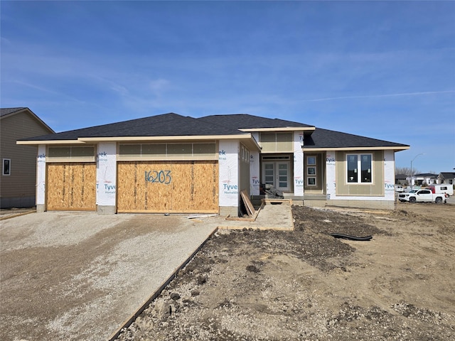 unfinished property with a garage, driveway, and a shingled roof