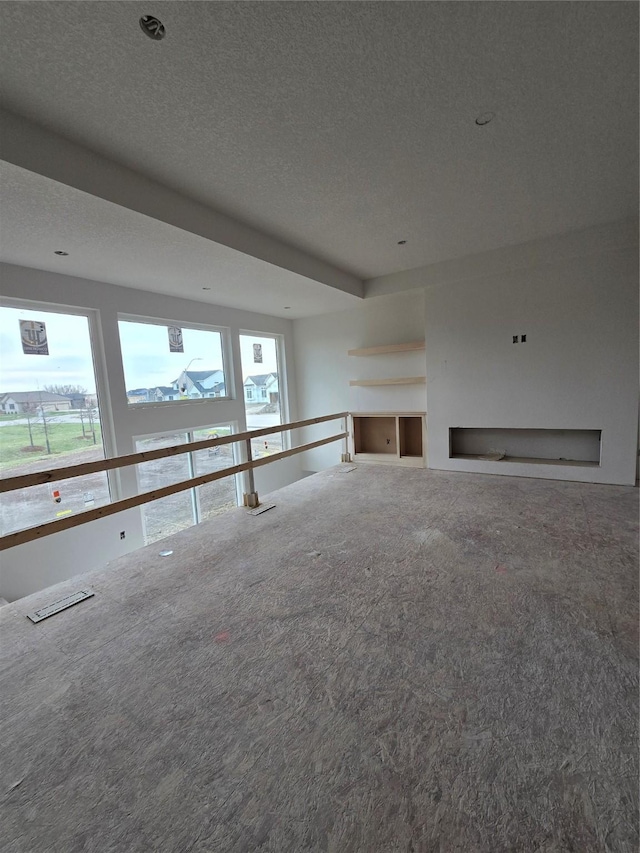 unfurnished living room featuring a fireplace, carpet floors, and a textured ceiling