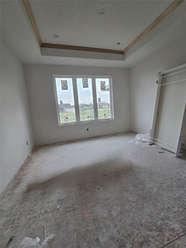 carpeted spare room with a tray ceiling and ornamental molding
