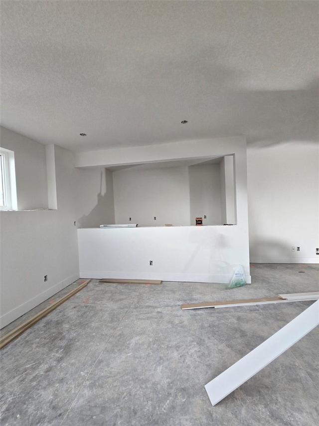 unfurnished room with baseboards and a textured ceiling