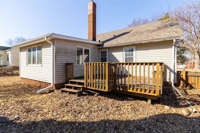 rear view of property featuring a wooden deck, roof with shingles, a chimney, and fence