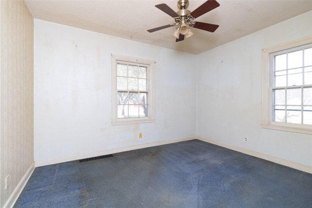 empty room with visible vents, baseboards, and dark carpet