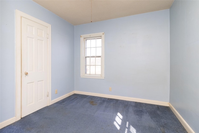 unfurnished room featuring baseboards and dark carpet