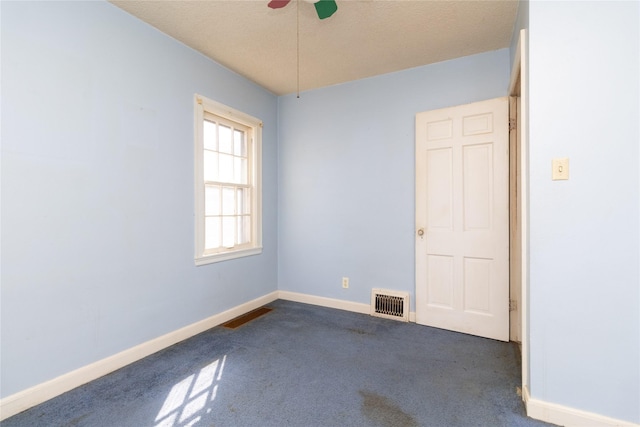 unfurnished room featuring a ceiling fan, baseboards, visible vents, and dark carpet