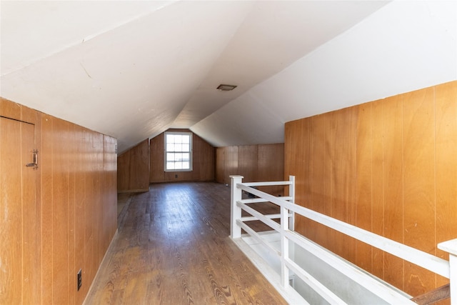 bonus room with wooden walls, lofted ceiling, and wood finished floors