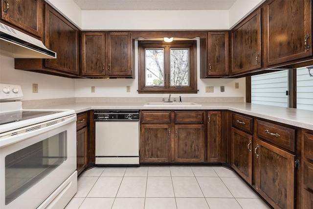 kitchen featuring under cabinet range hood, dark brown cabinets, white appliances, and a sink