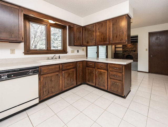 kitchen featuring light countertops, a peninsula, white dishwasher, and a sink