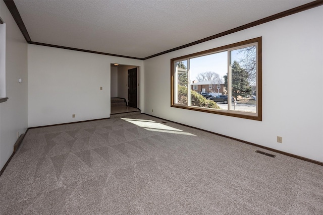 carpeted empty room with visible vents, a textured ceiling, crown molding, and baseboards