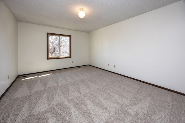 unfurnished room with baseboards, carpet floors, and a textured ceiling