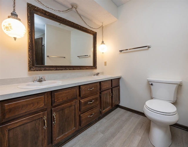 bathroom featuring double vanity, toilet, wood finished floors, and a sink