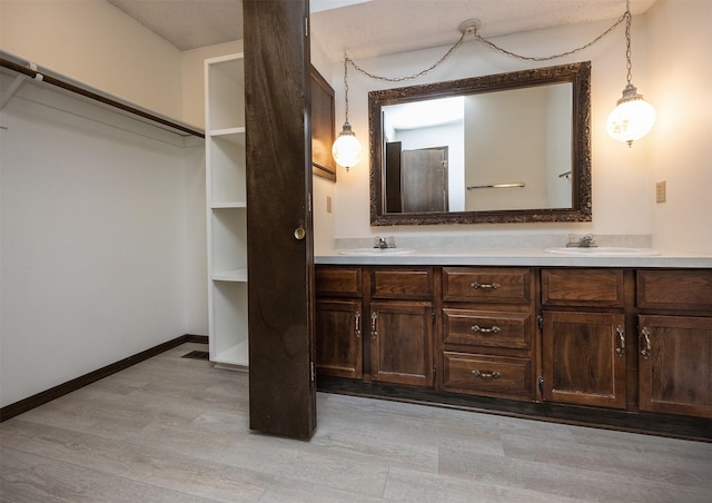 full bathroom with double vanity, wood finished floors, baseboards, and a sink