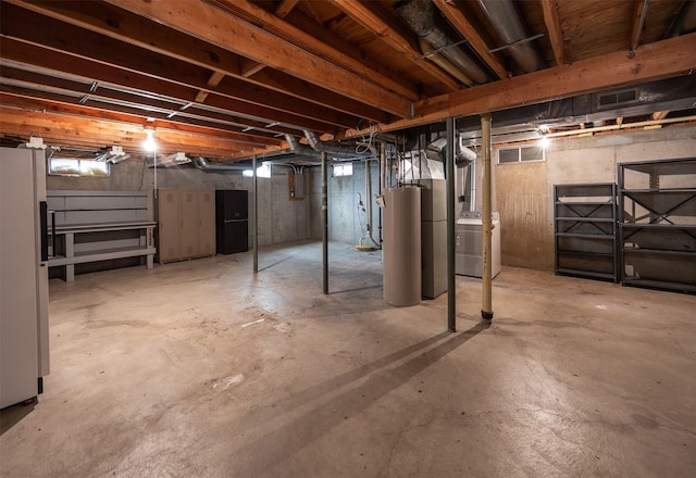 unfinished basement with washer / dryer, gas water heater, visible vents, and freestanding refrigerator