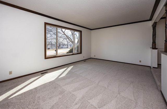 empty room featuring visible vents, light carpet, a textured ceiling, crown molding, and baseboards