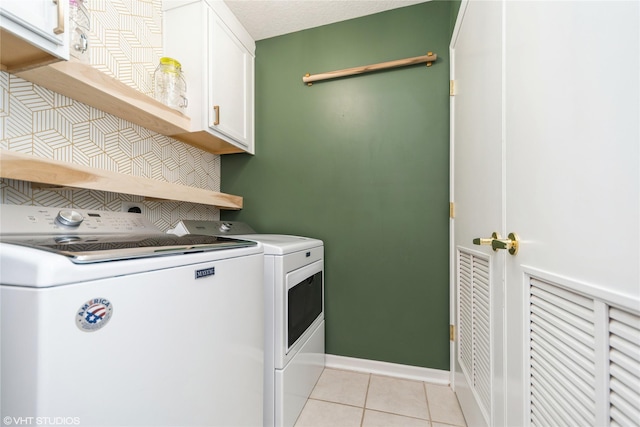 washroom with baseboards, light tile patterned flooring, cabinet space, a textured ceiling, and independent washer and dryer