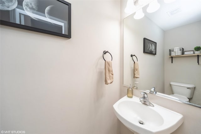 bathroom featuring a sink, visible vents, and toilet