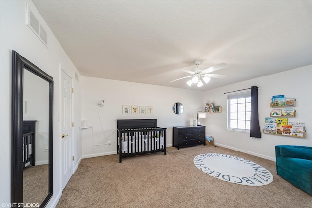 bedroom with visible vents, baseboards, carpet, a textured ceiling, and a nursery area