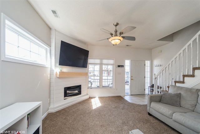 carpeted living room with visible vents, plenty of natural light, ceiling fan, and stairs