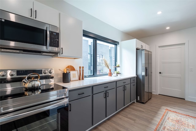 kitchen featuring gray cabinetry, recessed lighting, stainless steel appliances, light wood-style floors, and light countertops