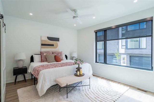 bedroom with wood finished floors, recessed lighting, and baseboards