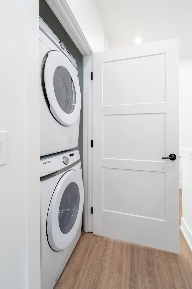 laundry area with laundry area, stacked washer / dryer, and wood finished floors