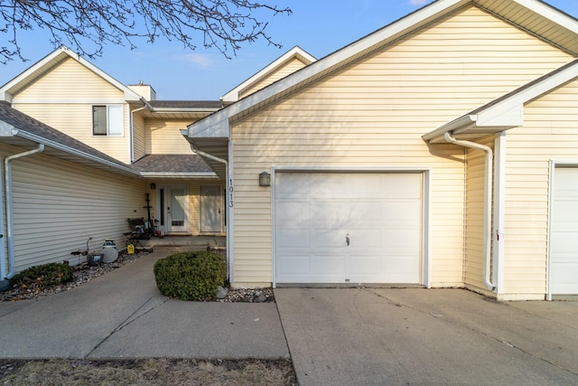 view of home's exterior with an attached garage, concrete driveway, and roof with shingles