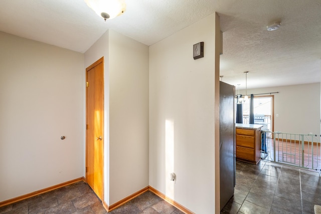 hall featuring baseboards and a textured ceiling