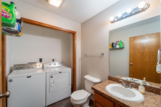 bathroom featuring toilet, vanity, and separate washer and dryer