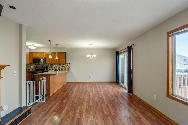 living area featuring dark wood-style floors, a notable chandelier, and baseboards