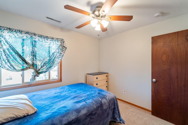 bedroom featuring visible vents, light colored carpet, a ceiling fan, and baseboards