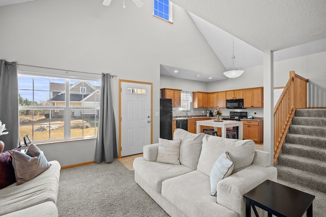 living room with ceiling fan, baseboards, stairway, light carpet, and high vaulted ceiling