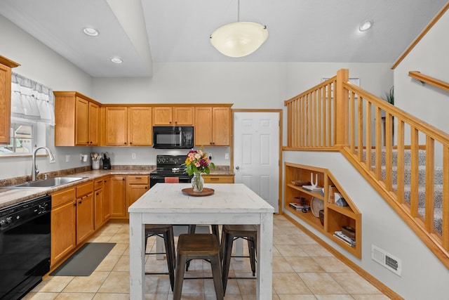 kitchen featuring light tile patterned floors, visible vents, black appliances, and a sink