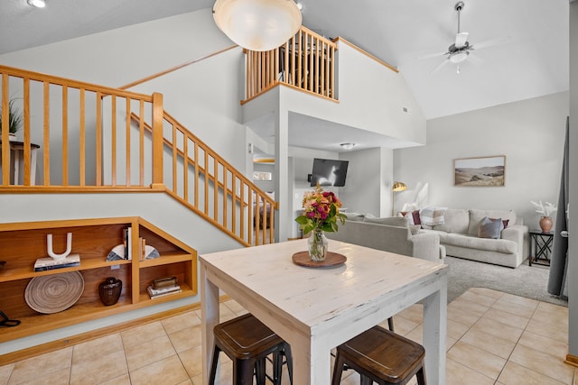 carpeted dining area with tile patterned floors, visible vents, high vaulted ceiling, a ceiling fan, and stairs