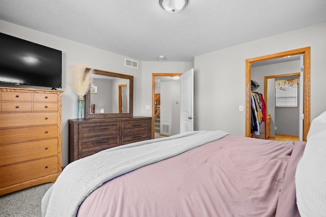 bedroom featuring visible vents, a textured ceiling, and carpet flooring