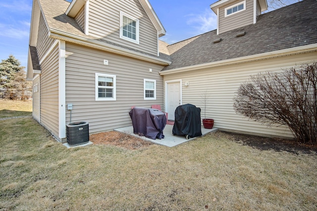 rear view of house featuring cooling unit, a patio, a lawn, and a shingled roof