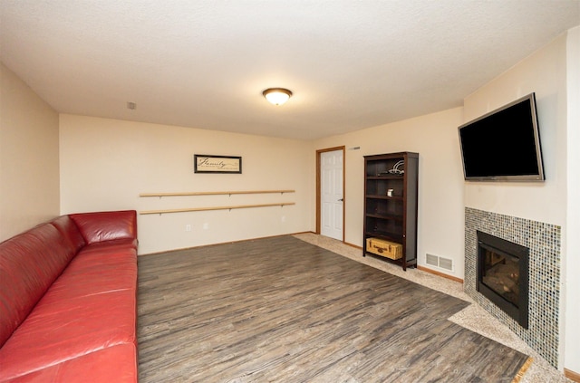 living area featuring wood finished floors, visible vents, and a tile fireplace