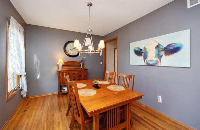 dining area with light wood-style flooring, baseboards, visible vents, and a chandelier